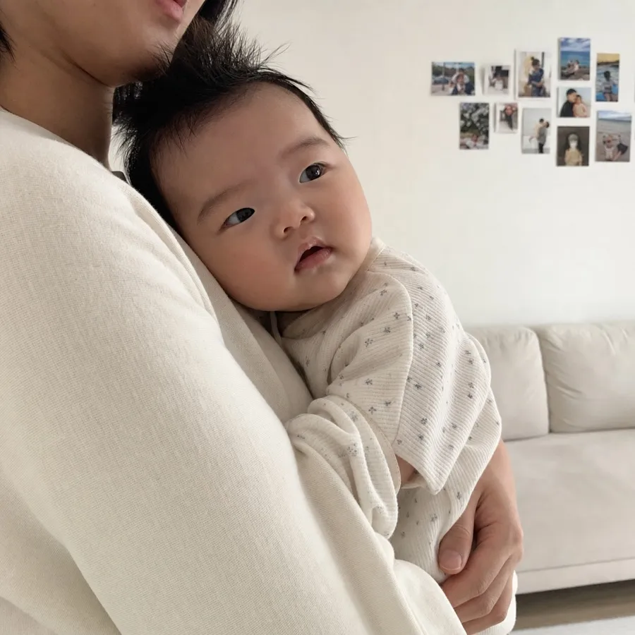 이불 위에 앉아 있는 아기 사진